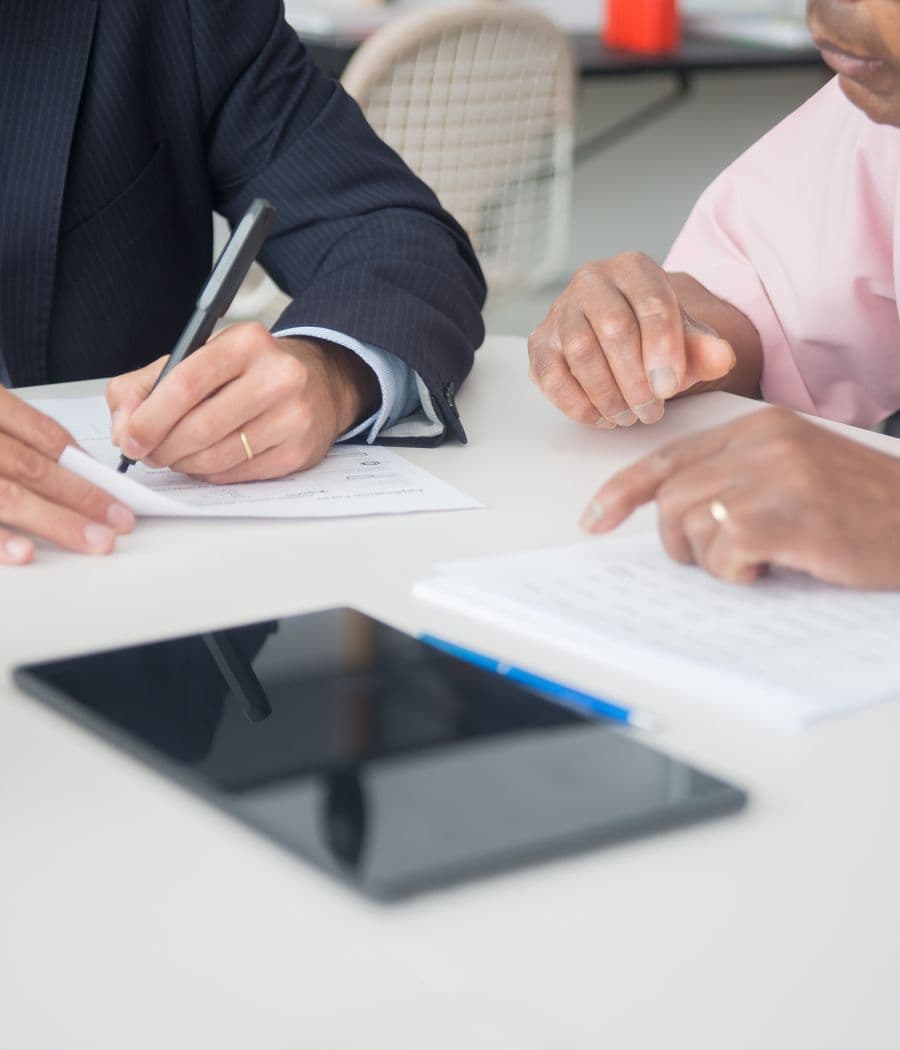 Two people signing an agreement across a desk